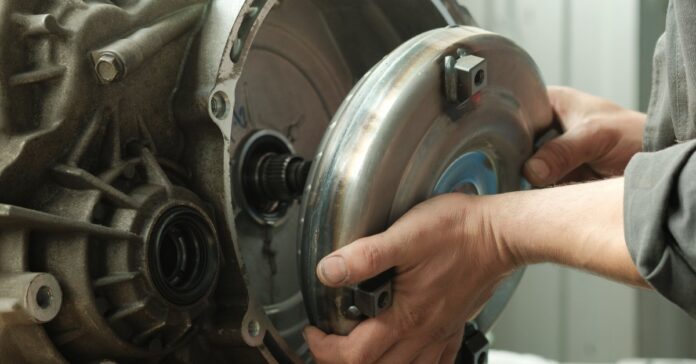 Close-up of a mechanic's hands as they install a brand new torque converter on an automatic transmission.