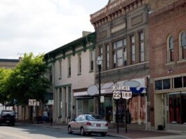Can Your Business Find Success in a Smaller Town? A strip of old businesses in a small Midwestern downtown area. There are a few cars parked on the street.