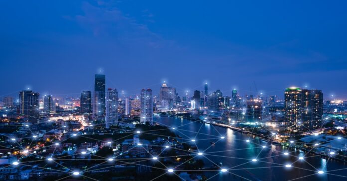 A large city at night with multiple tall buildings and the lights on, with a digital light web connecting them all.