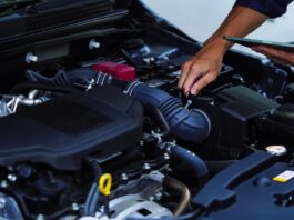 3 Smart Ways to Save Money on Car Repairs A person with their sleeves rolled up holding a tablet and using a small screwdriver to repair a car.