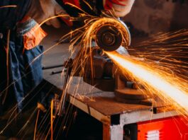 How To Make Your Metal Cutting Tools Last Longer A worker uses a hand saw to cut at a piece of metal. A shower of sparks is flying off of the saw blade.