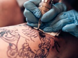 How to Make Your First Year as a Tattoo Artist Successful A person who is wearing blue gloves is holding a tattooing needle and is using it one another person.
