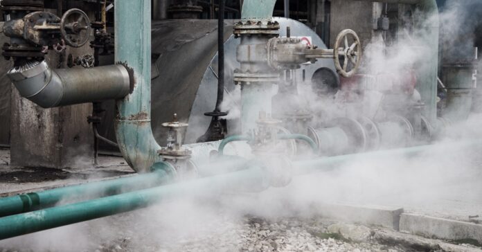 The exterior of a business where the steam system is located. The pipework is old and there is active steam rising.