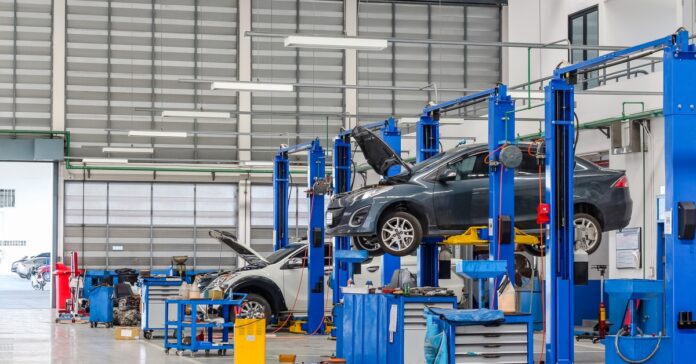 An auto repair shop with multiple vehicles on hydraulic lifts, tool cabinets, and service equipment inside a garage.