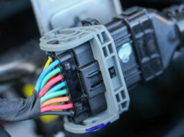 How to Tell if Your Car Connectors Are Still Good A close-up of colored electrical wires connected to a black and gray plug inside a vehicle engine bay.
