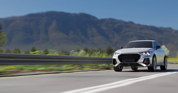 A clean gray car driving fast down the highway during the daytime. A large mountain is visible in the distance.