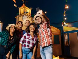 A group of friends wearing cowboy hats and plaid shirts pose together at a colorful Western-themed celebration.