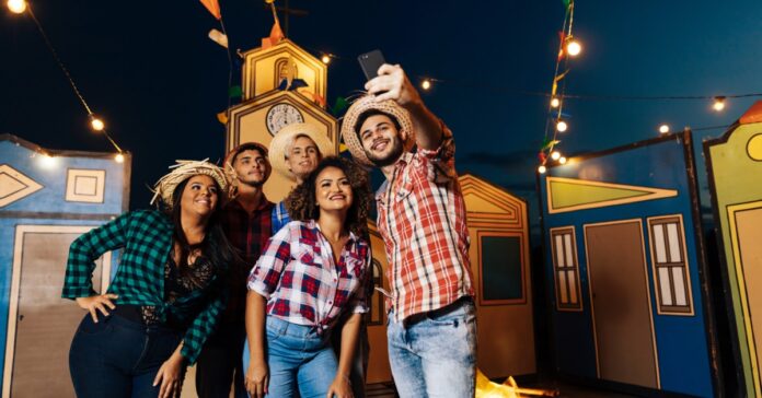 A group of friends wearing cowboy hats and plaid shirts pose together at a colorful Western-themed celebration.